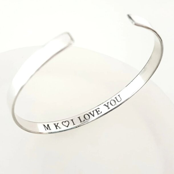 Personalised silver cuff bracelet engraved with "mx I love you," showcasing a heartfelt message.