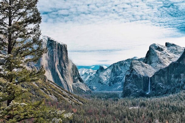 Panoramic landscape of Yosemite National Park, featuring majestic granite cliffs and vibrant greenery in California.  