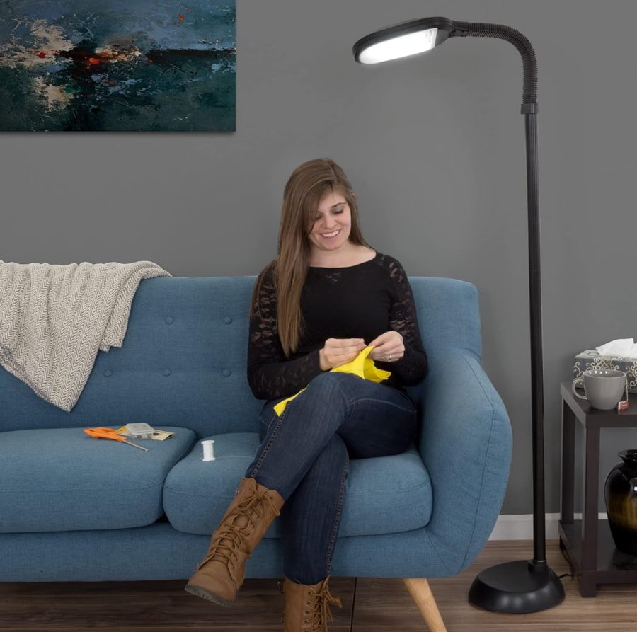 Woman sewing on blue couch with floor lamp