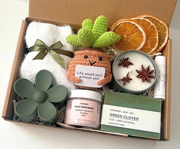 A box with a crocheted cactus, several candles, and other decorative items, showcasing a charming arrangement.