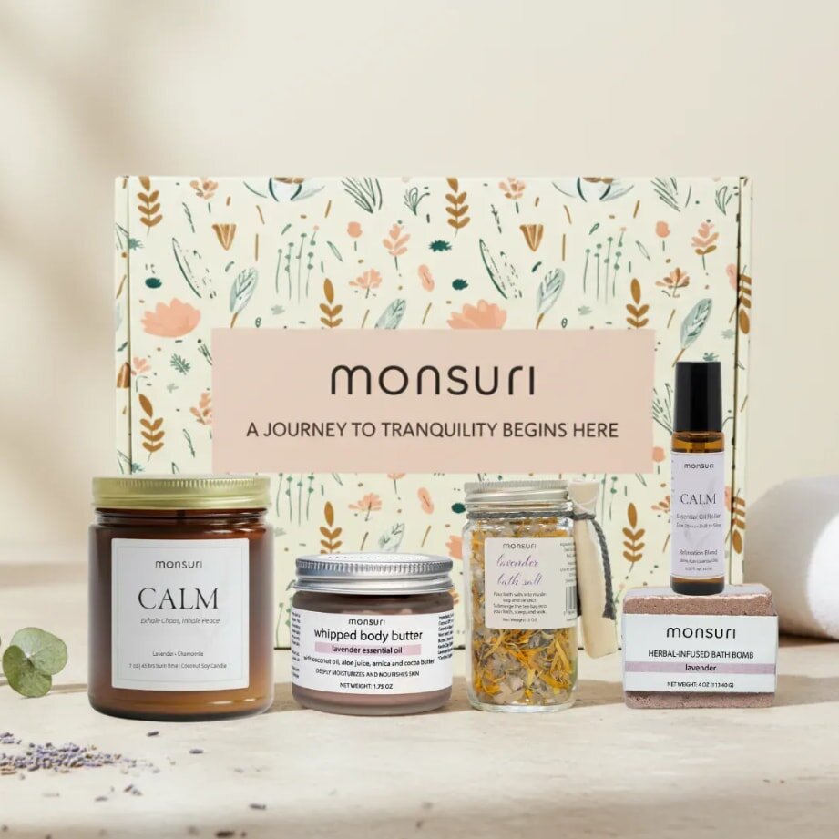 Gift set labeled "Monsuri" features calming products like a candle, body butter, bath bomb, and essential oil. Soft, floral packaging conveys tranquility.