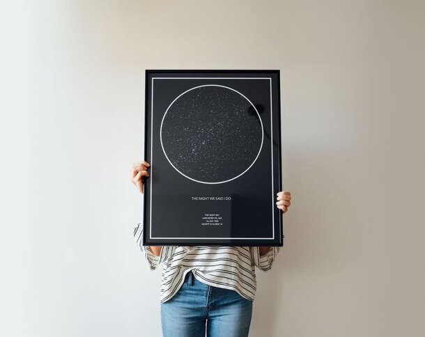 A woman holds a poster against a black background, showcasing her message with confidence and clarity.