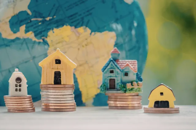 Small model houses on stacks of coins representing property investment and housing finance.