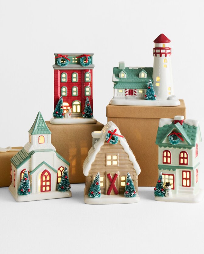 Festive ceramic Christmas village featuring illuminated houses, a church, and a lighthouse decorated with holiday details.