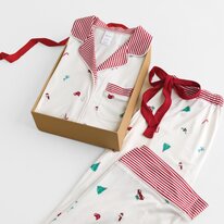 White holiday pajamas with red striped trim and tiny festive motifs, displayed in a gift box with a coordinating pajama top.