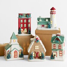 Festive ceramic Christmas village featuring illuminated houses, a church, and a lighthouse decorated with holiday details.