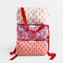 Three stacked floral cosmetic bags in pink and coral patterns, finished with red ribbon handles and bows.