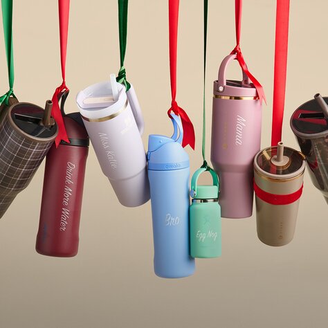 a display of personalized water bottles and tumblers hanging from colorful ribbons.