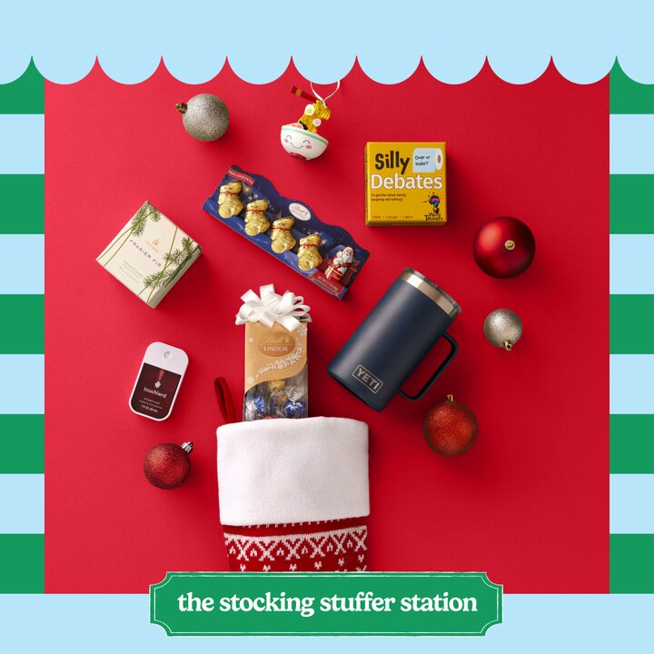 Stocking stuffer gift ideas on a red background featuring a yeti mug, a holiday scented candle, a card game, an ornament, and other items