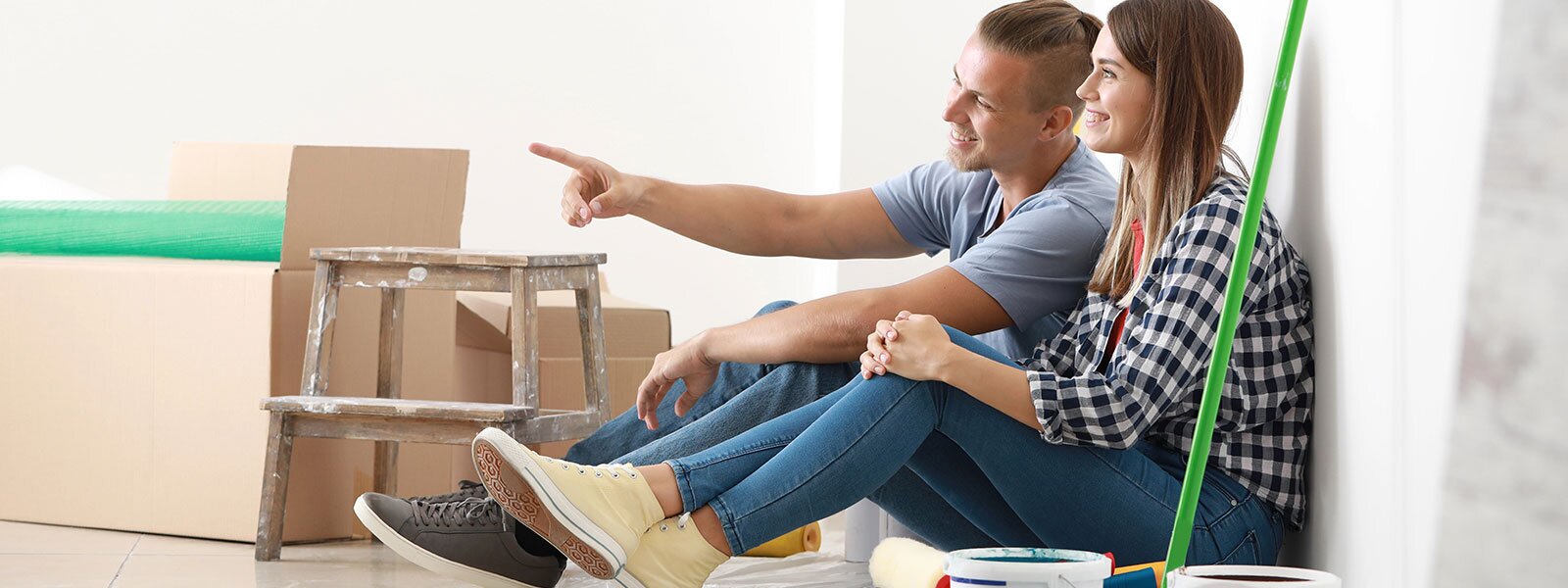 A couple sits in their new home, happily taking a break from painting to envision their plans.