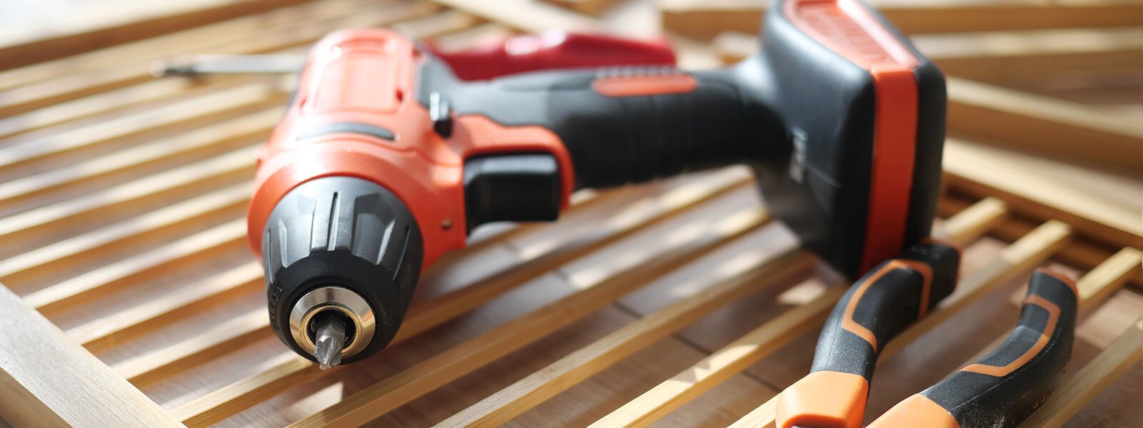 A drill and other tools lay on wooden slates.