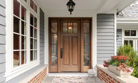 A front porch with a wooden door and white framed windows.
