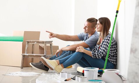 A couple sits in their new home, happily taking a break from painting to envision their plans.