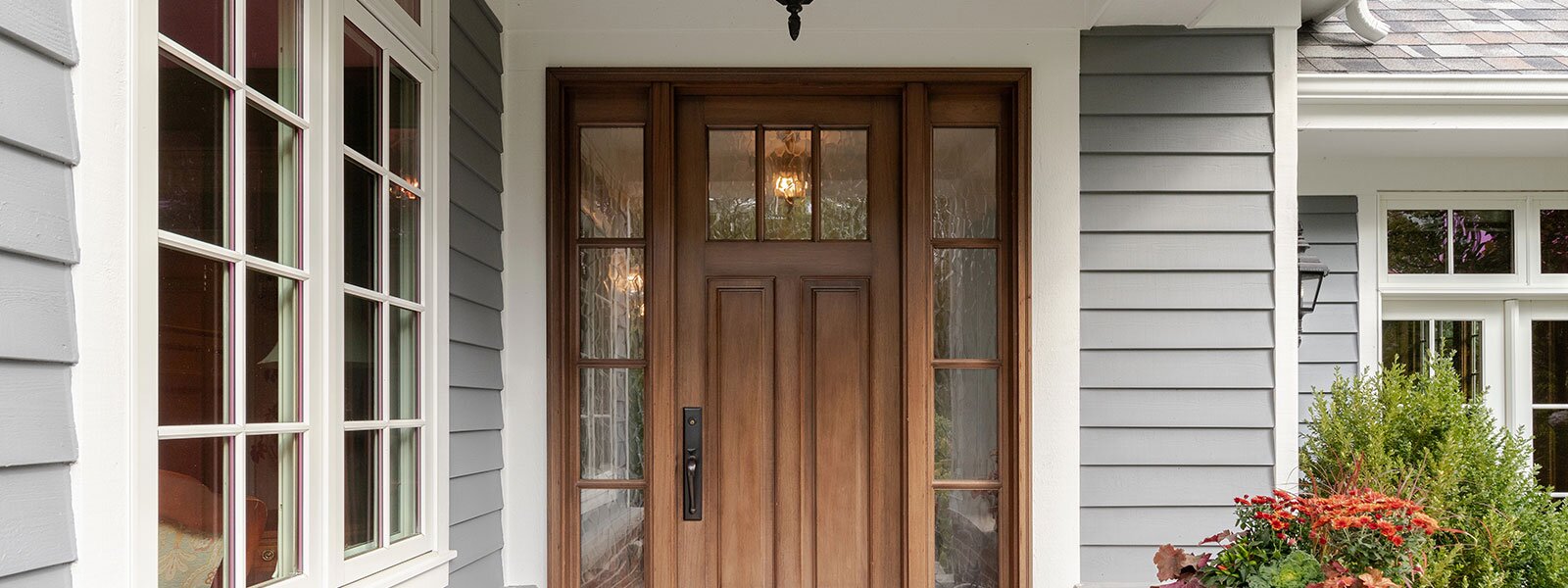 A front porch with a wooden door and white framed windows.