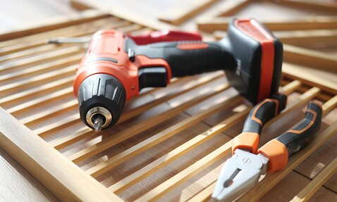 A drill and other tools lay on wooden slates.