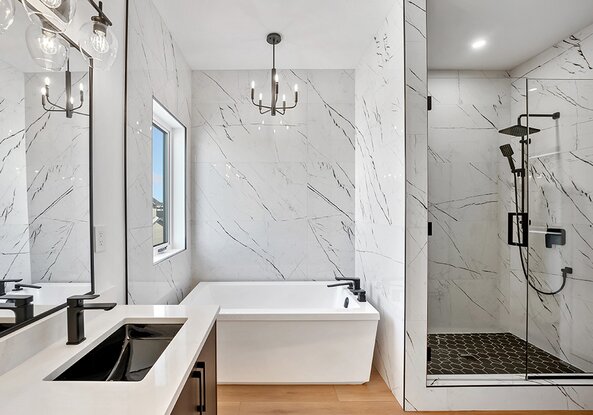 A beautiful, clean bathroom with marble tile and black features. 