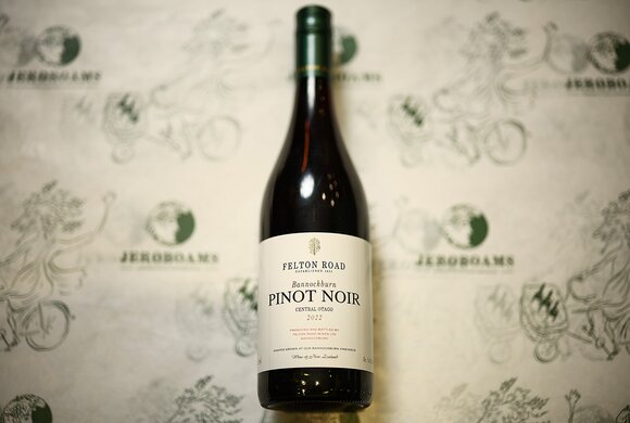 Glass of white wine beside a bottle of Château d'Yquem 2023 against a dark background