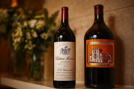 Glass of white wine beside a bottle of Château d'Yquem 2023 against a dark background