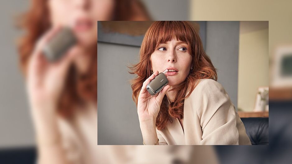 Žena se zrzavými vlasy používá Ploom X Advanced zařízení.