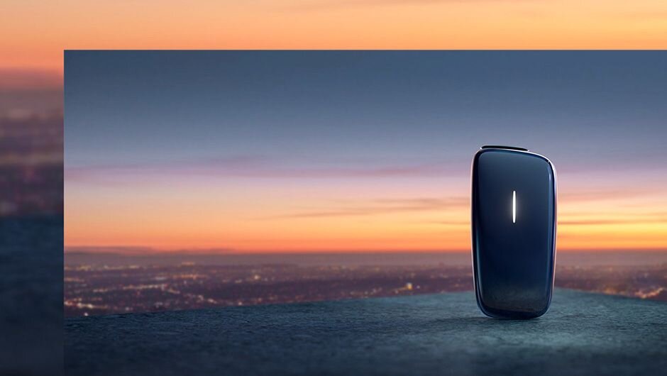 Západ slunce nad městem v popředí Navy Blue Ploom X Advanced zařízení.