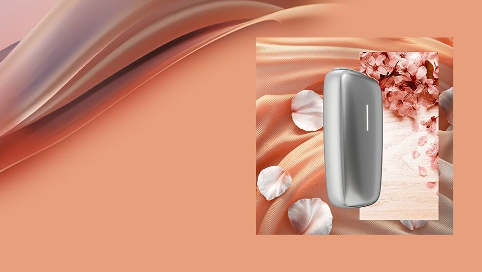 Stříbrné zařízení Ploom X Advanced s oranžovým květinovým pozadím.