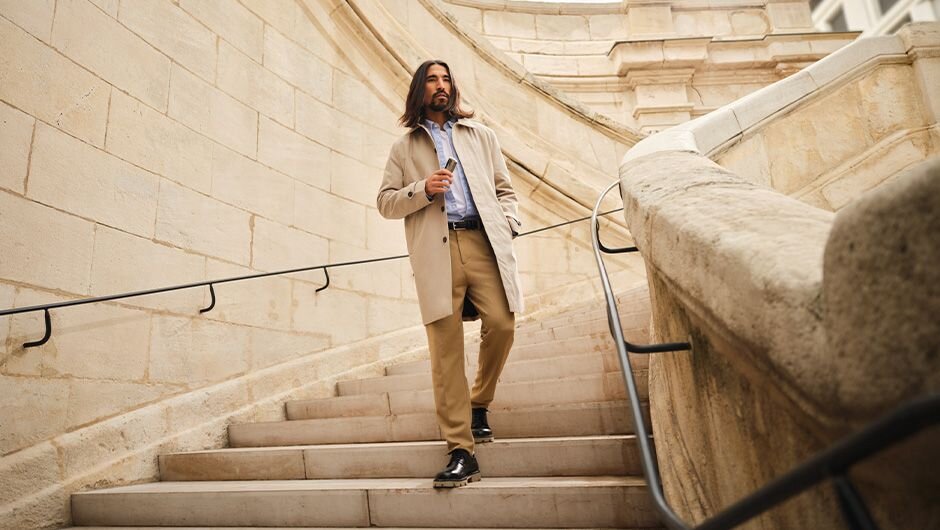 Muž jdoucí po kamenném schodišti držící v ruce zařízení Ploom X