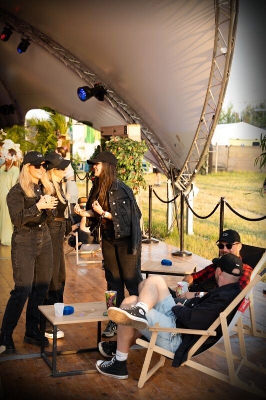 Hosté si užívají nápoje a Ploom ve stanu na festivalu v lehátkách