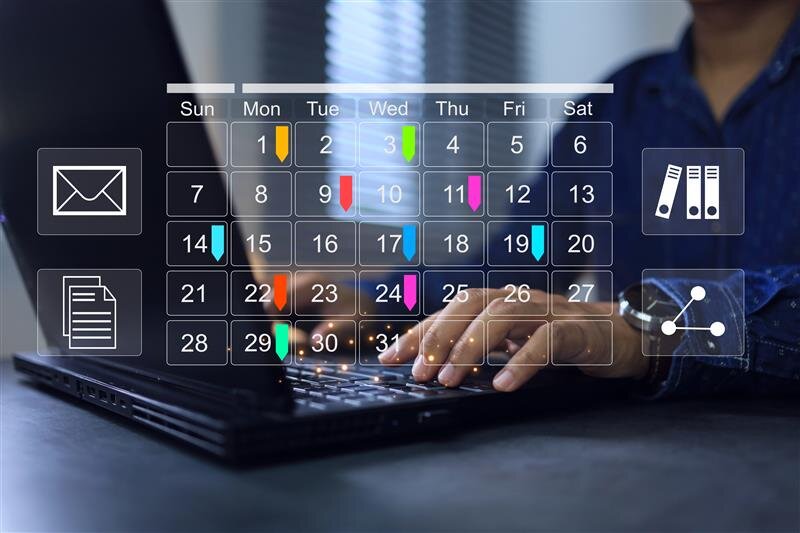 Ein Mann sitzt vor einem Laptop und tippt darauf. Über das Bild ist eine transparente Grafik von einem Kalender gelegt.