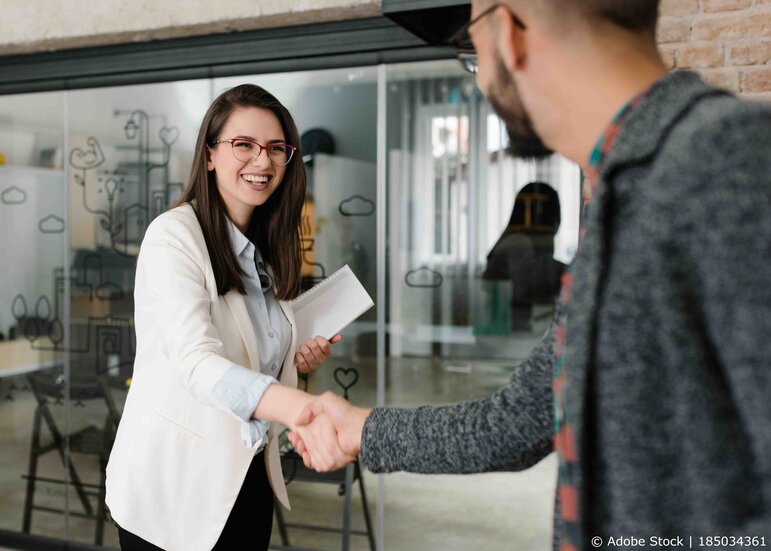 Eine neue Mitarbeiterin wird beim Onboarding mit Händedruck begrüßt