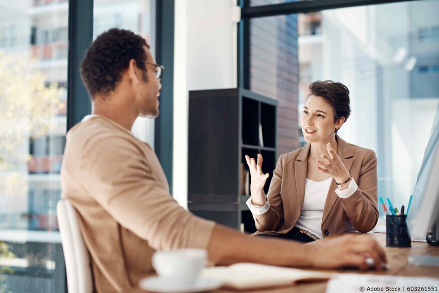 Zwei Personen, die ein vertrautes Gespräch im Büro führen.