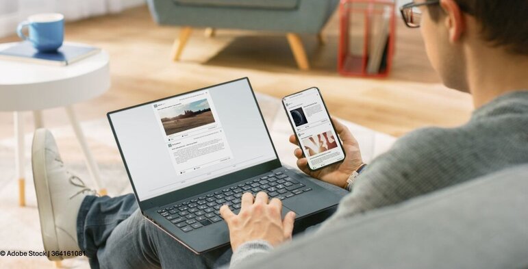 Eine Person nutzt entspannt Laptop und Smartphone gleichzeitig und erhält Unterstützung durch den digitalen Assistenten Silly.
