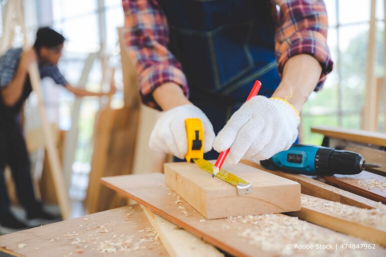 Handwerker misst Holzstück