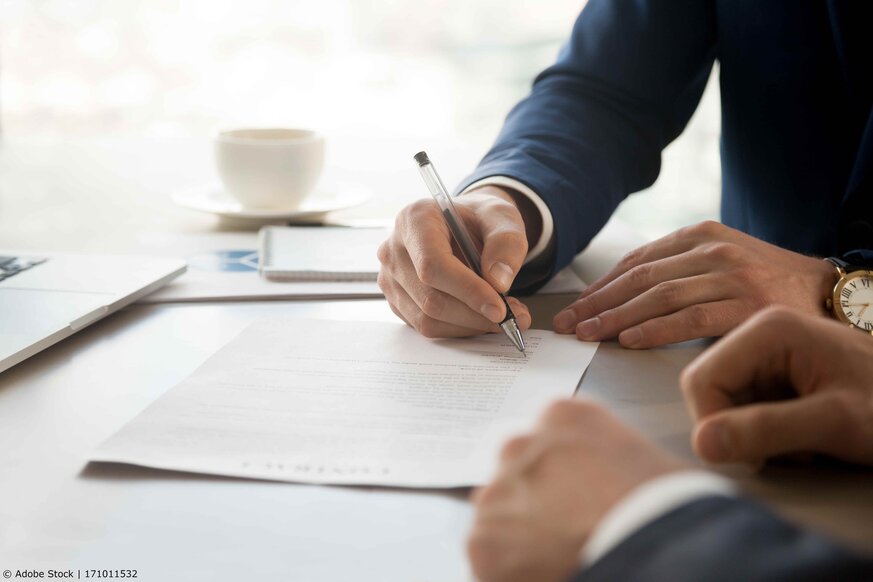 Hands of a man in a suite who is signing a contract