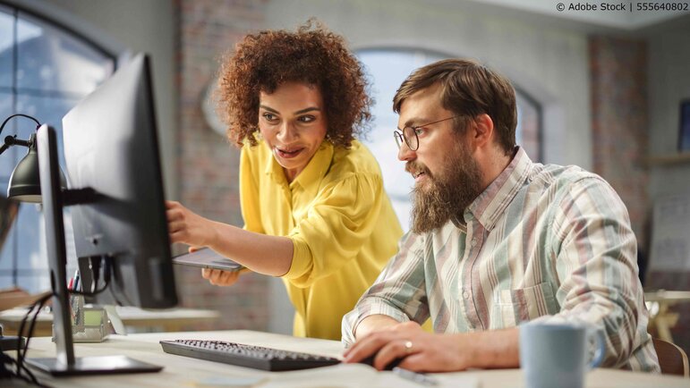 Zwei Personen, die gemeinsam an einer Onboarding-Aufgabe am Computer arbeiten