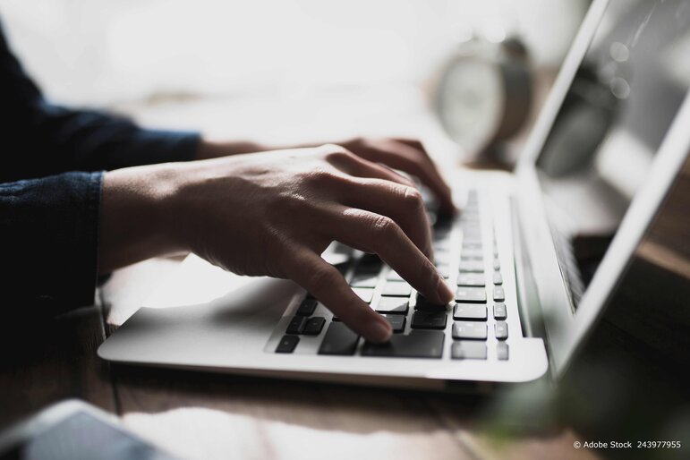 Ein Softwareentwickler programmiert an mehreren Bildschirmen in einer modernen digitalen Arbeitsumgebung.