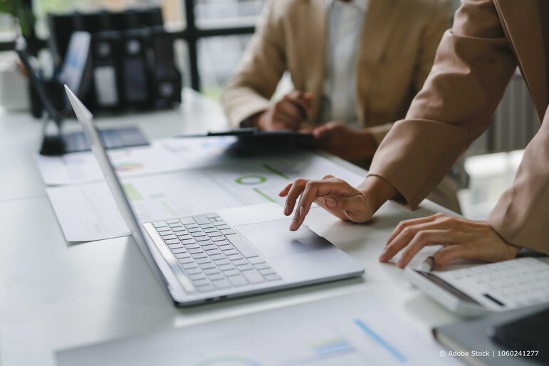 Zwei Geschäftsleute analysieren gemeinsam Unternehmenskennzahlen und Finanzdaten am Laptop, um fundierte Entscheidungen zu treffen. 