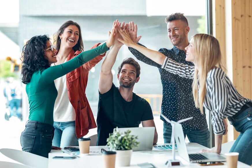 Eine Gruppe erfolgreicher Geschäftsteams feiert gute Arbeit und hält dabei ihre rechte Hand am Coworking-Platz