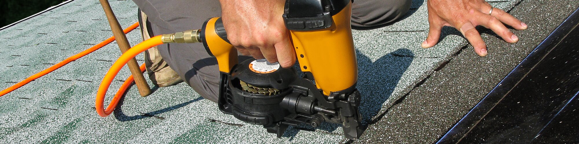 Worker using staple gun to fix roof