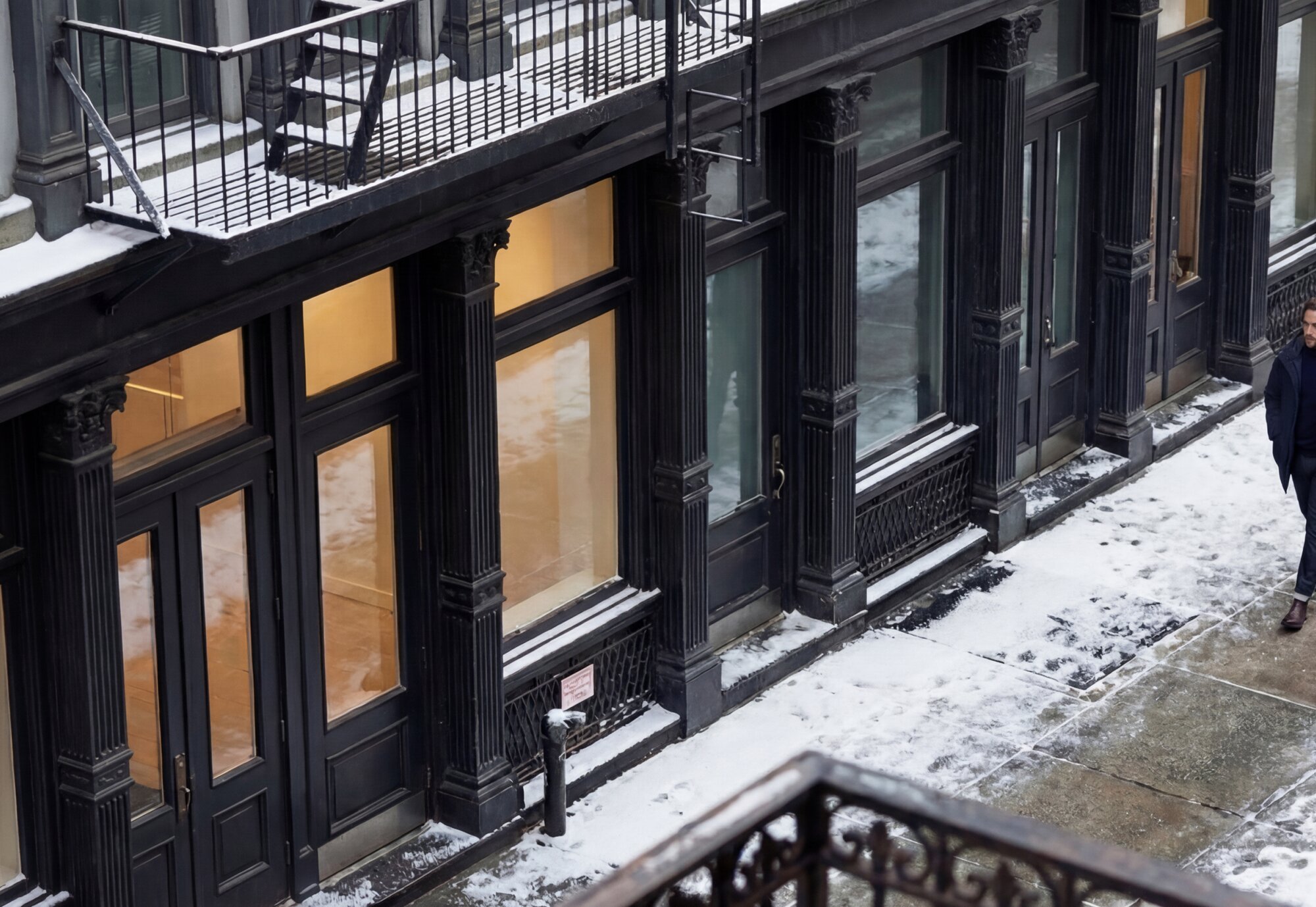 A snow-covered sidewalk seen from an upper-floor window.