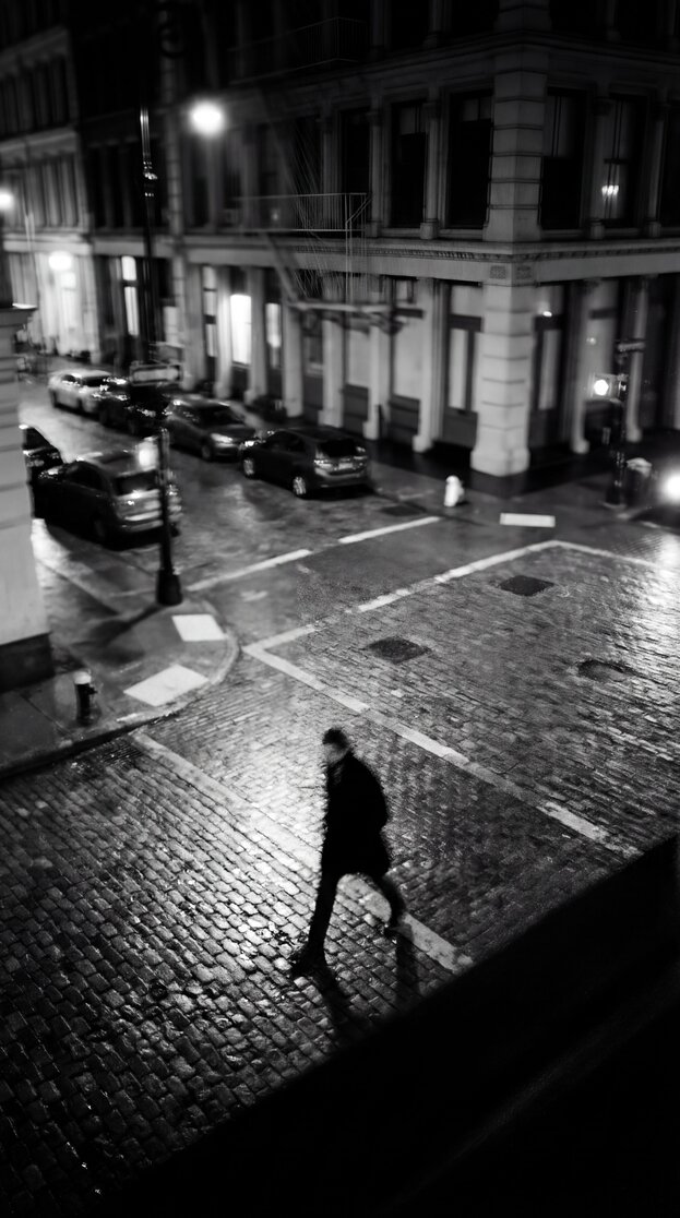 A man walking on a cobblestone street wearing suede tassel loafers.