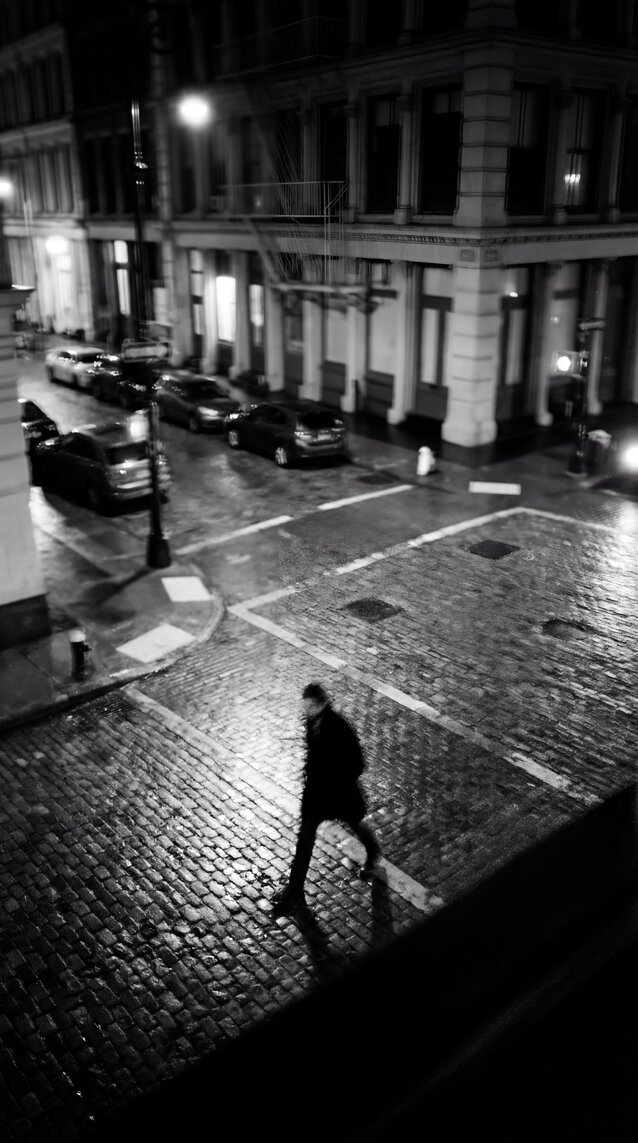 A man walking on a cobblestone street wearing suede tassel loafers.