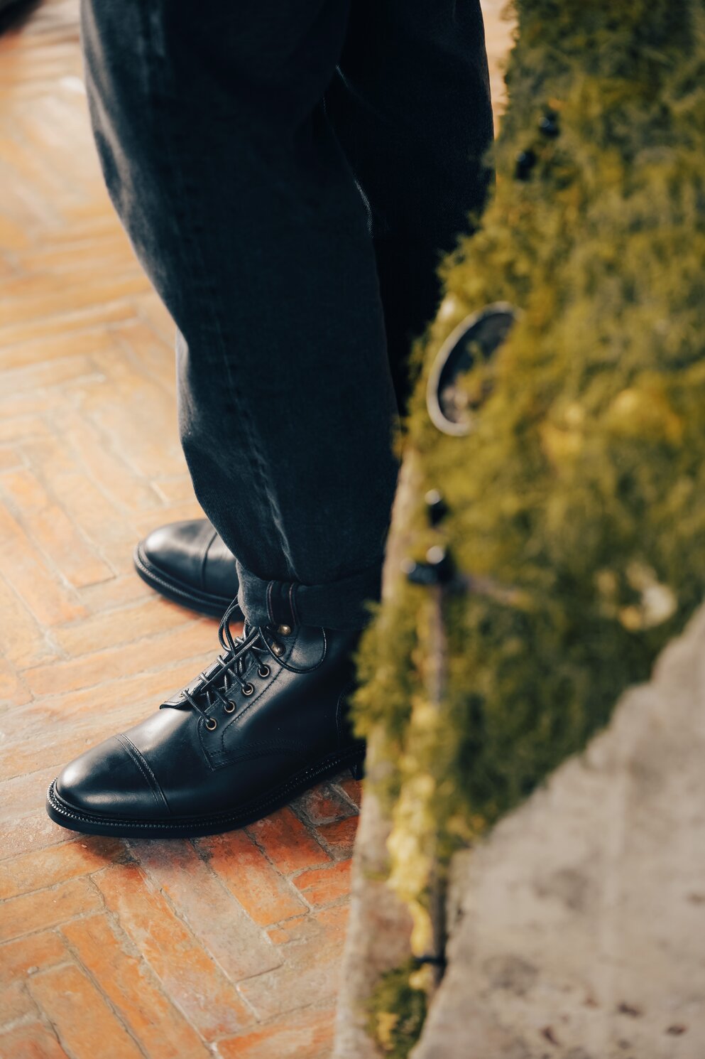 Person in black jeans wearing waxy calf boots.