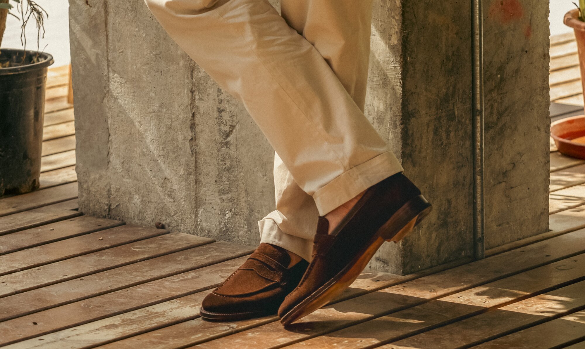 Person sitting on a curb wearing black shell cordovan leather loafers and white pants.