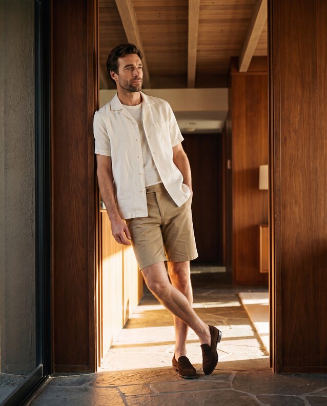 Model wearing a camp linen shirt, shorts and a brown suede penny loafer.