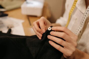 Sewing a button on a black garment