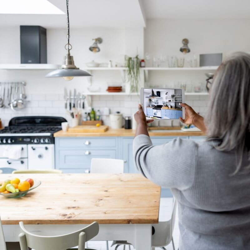 Renter using a tablet to scan the kitchen and dining area of a short-term rental with the Scansurance app to document property condition at check-in.