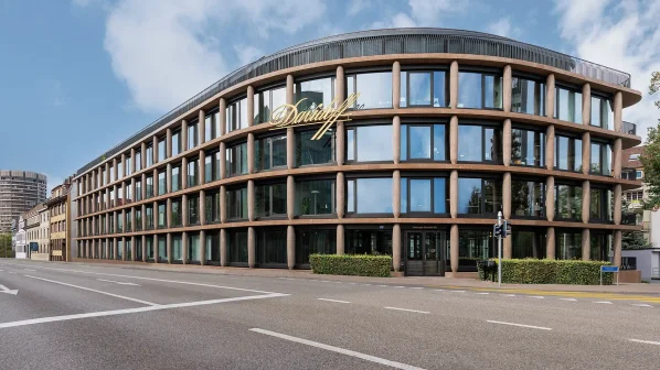 A modern curved building with large windows, showcasing office interiors, alongside a busy street in a cityscape.