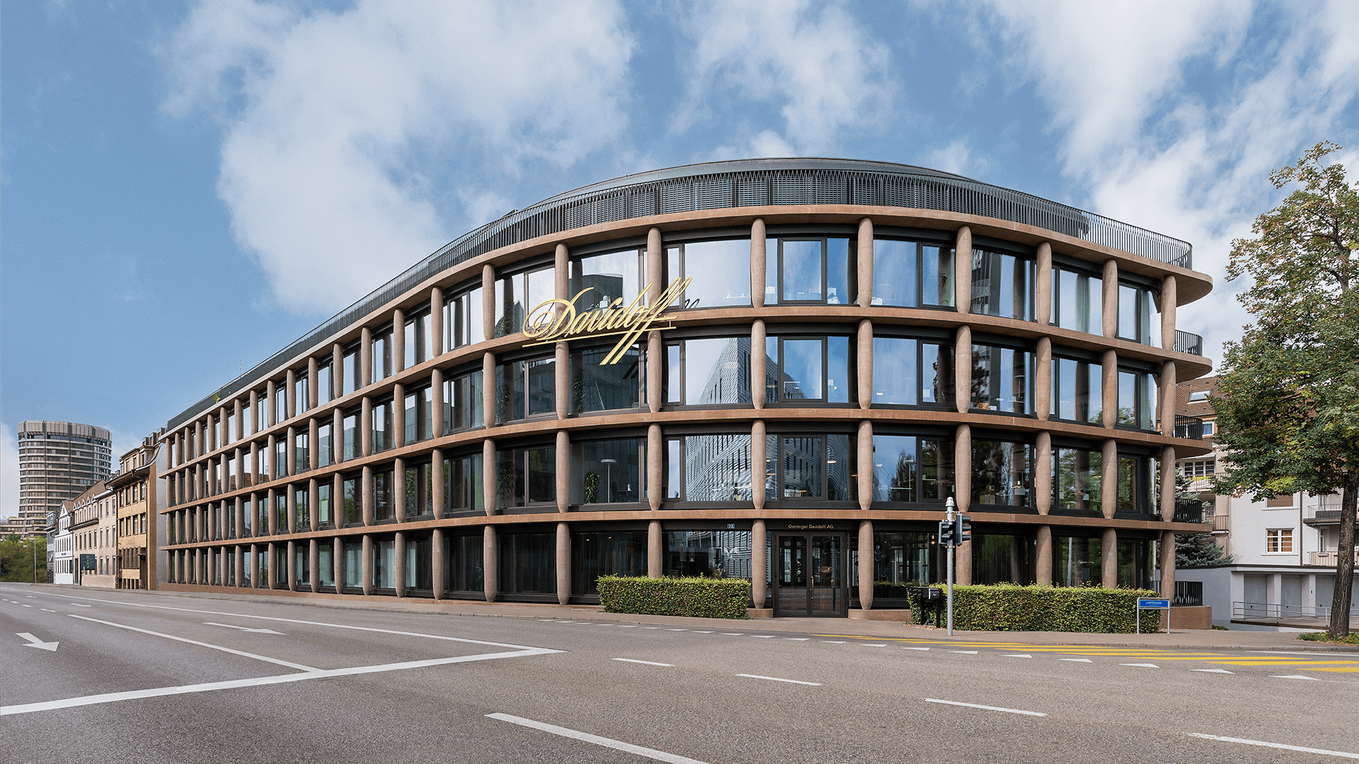 A modern glass building with an exterior facade featuring columns that resemble cigars. This is the Maison Davidoff building, serving as the headquarters in Basel.