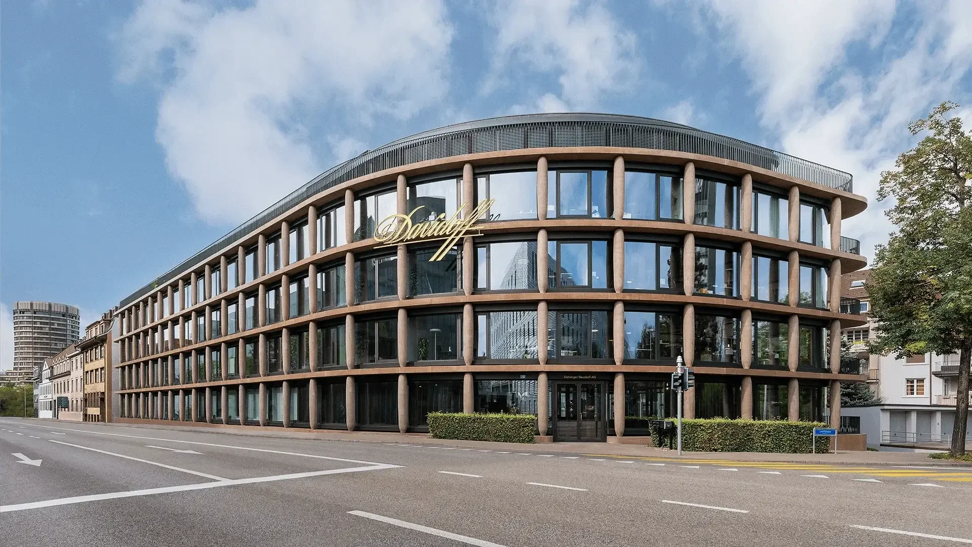 A modern glass building with an exterior facade featuring columns that resemble cigars. This is the Maison Davidoff building, serving as the headquarters in Basel.