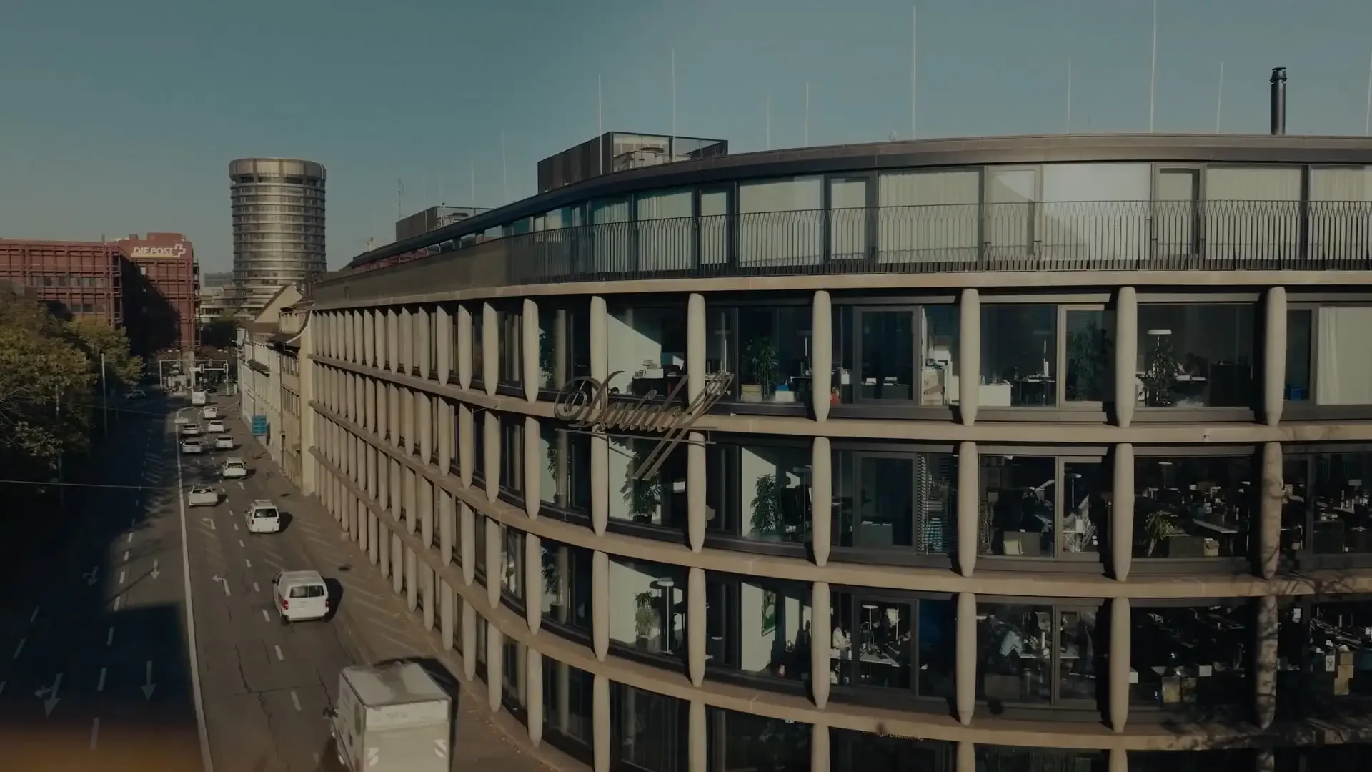A modern glass building with an exterior facade featuring columns that resemble cigars. This is the Maison Davidoff building, serving as the headquarters in Basel.
